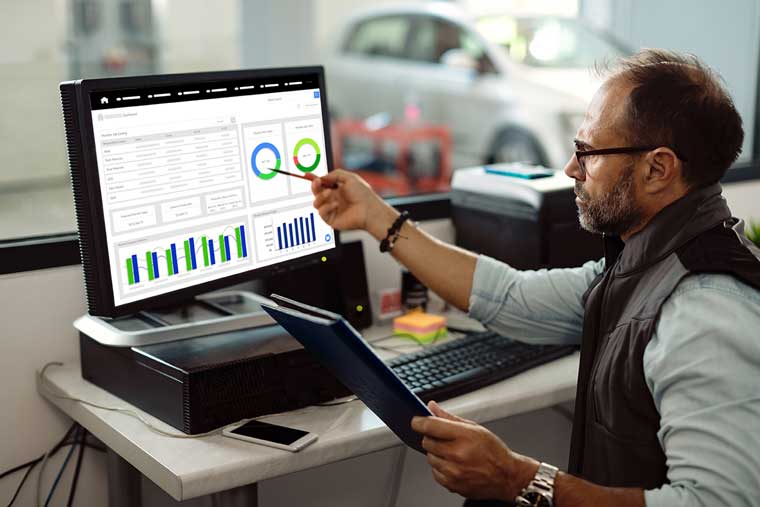 Auto body shop manager pointing at a computer screen displaying ImEX software